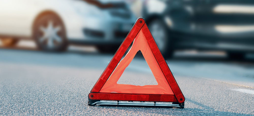 Orange caution sign near cars after an accident